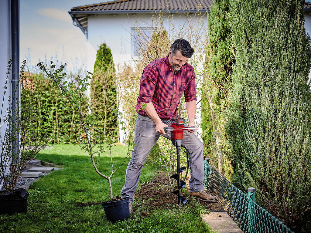 A man drills into the earth with an auger