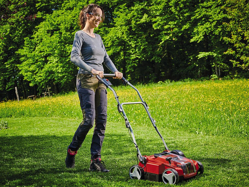 Woman using cordless scarifier for lawn care