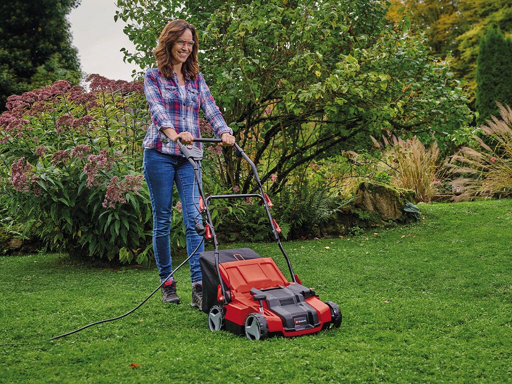Woman maintaining her lawn with an electric scarifier.