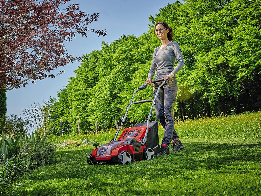 Woman scarifying a mown lawn.