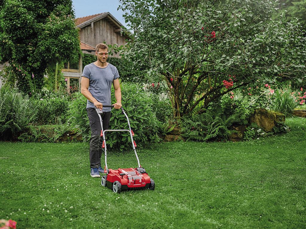 A man dethatching his lawn in long, straight paths.
