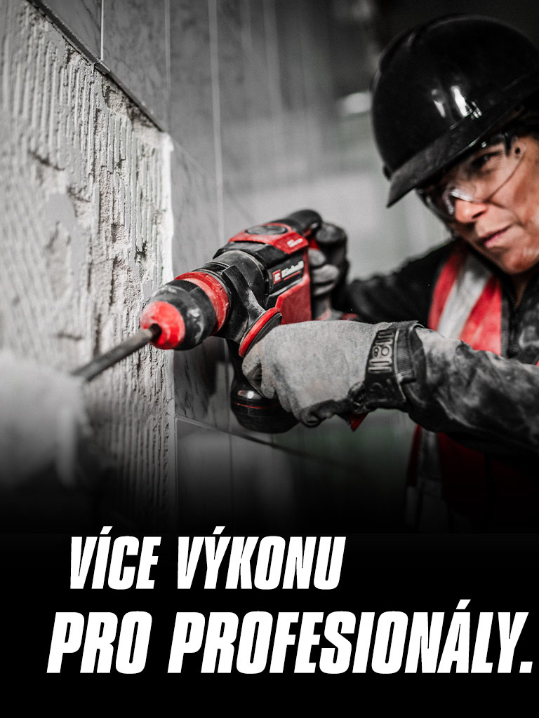 Osoba s ochrannými brýlemi a helmou používá červenou vrtačku na zdi s nápisem „More Power for Pros“.