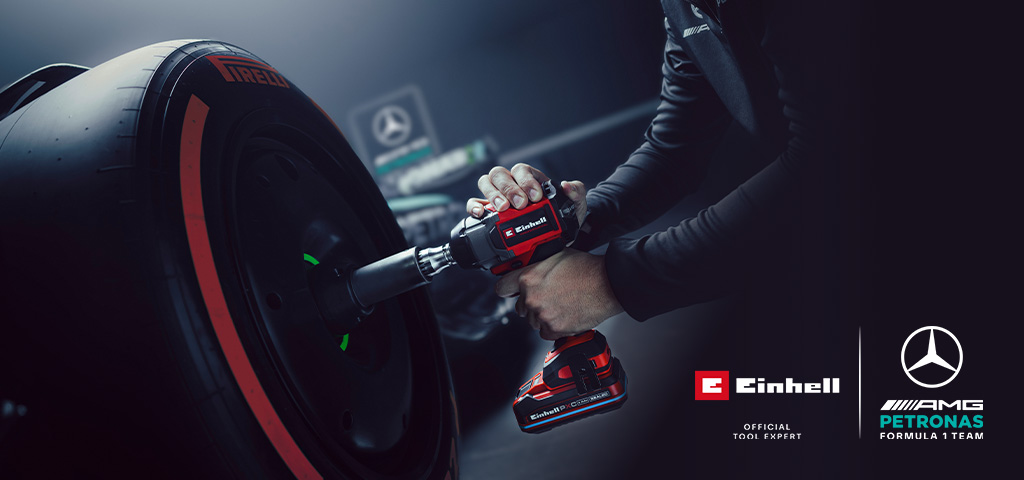 Akumulátorový rázový uťahovač Einhell pri použití na kolese automobilu, so značkou a logom partnerstva tímu Mercedes-AMG Petronas Formula One