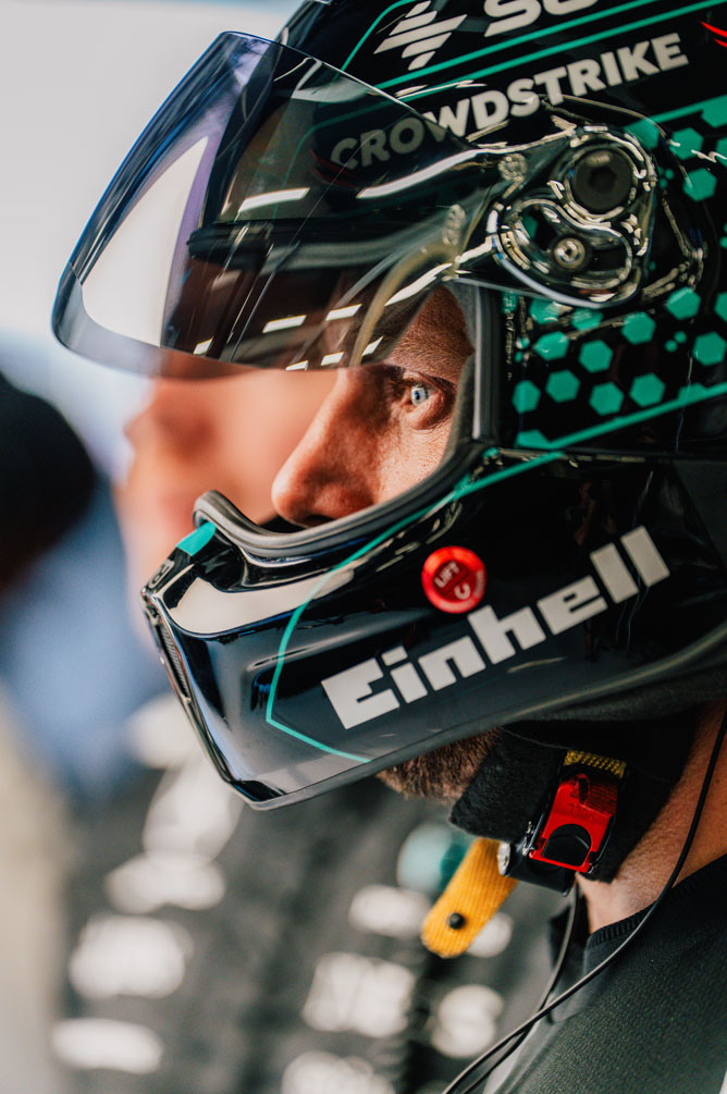 Bir Formula 1 ekip üyesi kask takıyor ve dikkatle yana bakıyor.