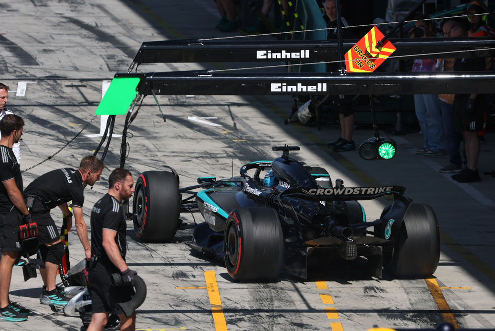 Vůz Mercedes-AMG PETRONAS Formula One Team je v boxové uličce během zastávky v boxech. Několik členů týmu je kolem auta. Logo Einhell je viditelné nad boxovou oblastí.