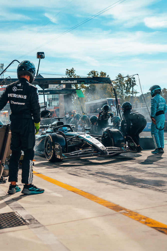 Intenzivní zastávka v boxech pro tým Mercedes-AMG PETRONAS Formula One Team. Tým je v plném nasazení, mění pneumatiky a kontroluje vůz pod portálem s logem Einhell.