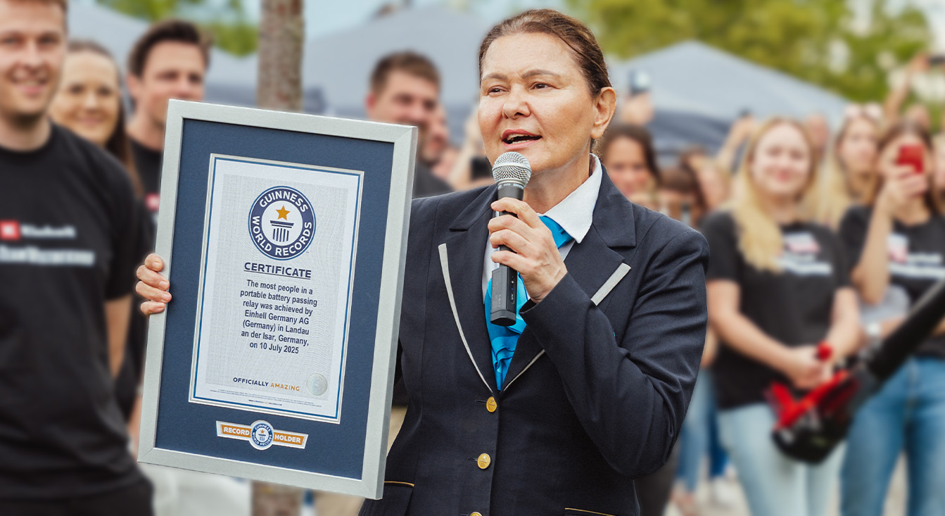Žena v oficiálním oblečení Guinness drží certifikát pro světový rekord v použití 300+ zařízení na jediný akumulátor Einhell.