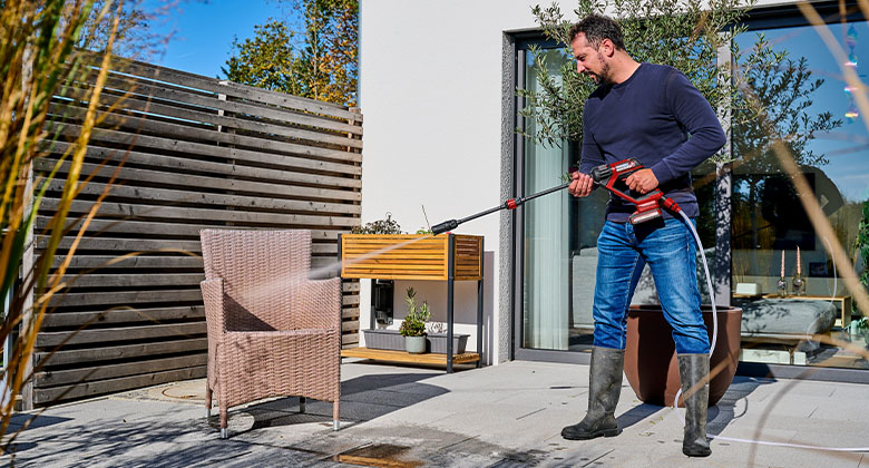 A man cleaning the garden chair with the high pressure cleaner