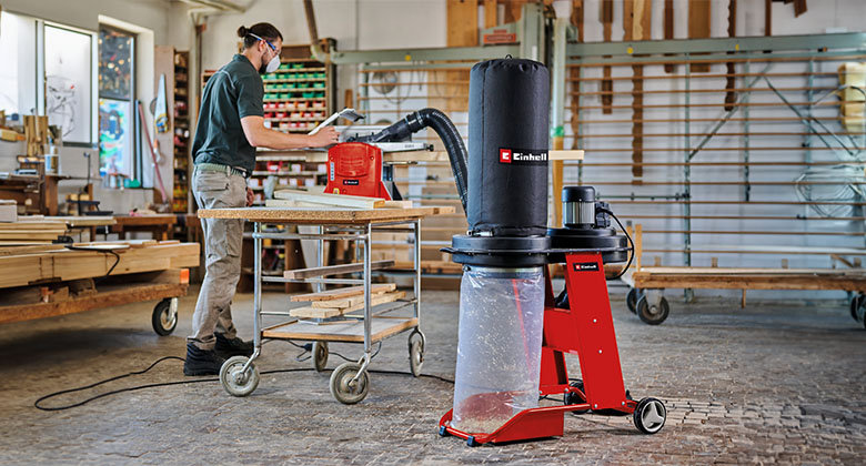 A man standing in his workshop and using the stationary machine